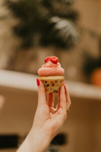 A cupcake with pink frosting and fresh raspberries