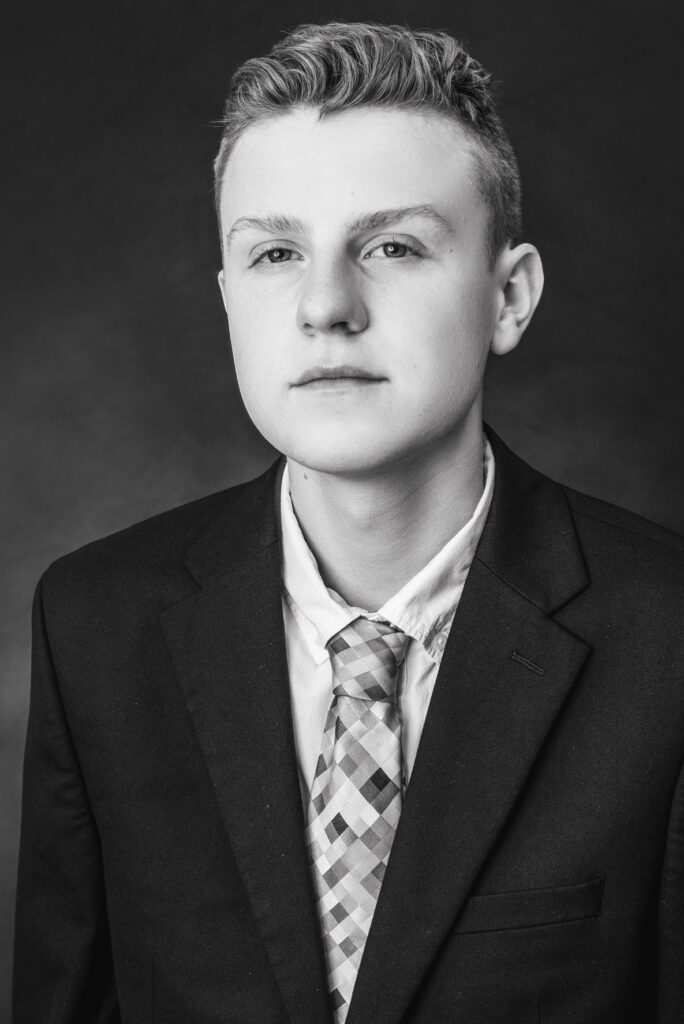 Black-and-white portrait of Alex Harrison wearing a suit and tie