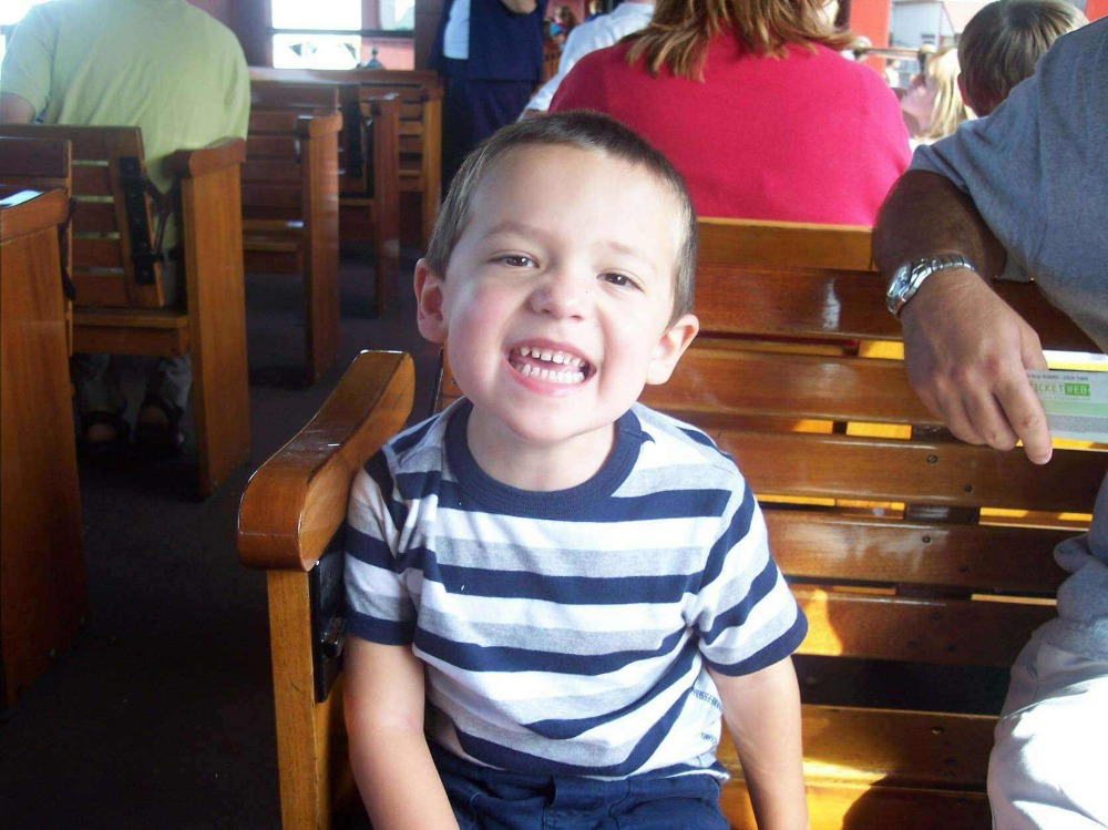 Cameron Boyd as a child smiling during a train ride