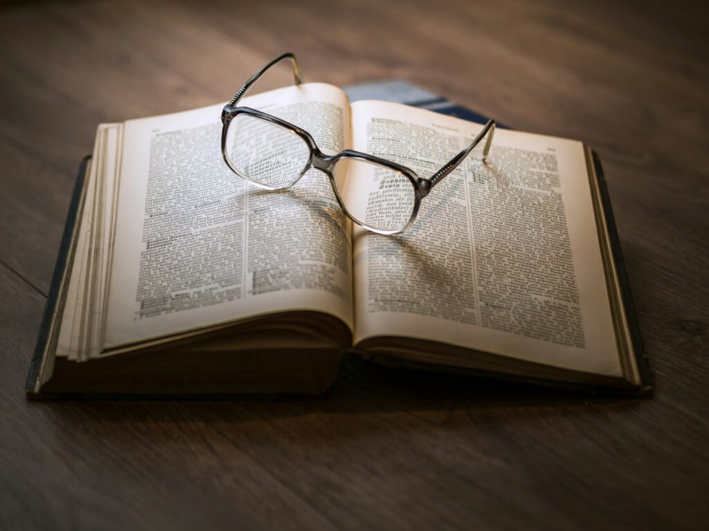 A pair of eyeglasses resting on the pages of an open book