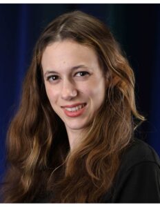 Isabella Grbac smiling in a headshot against a dark background.