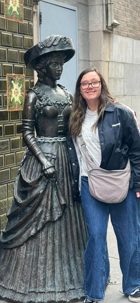 Jamie Boeckel standing beside a bronze statue outdoors