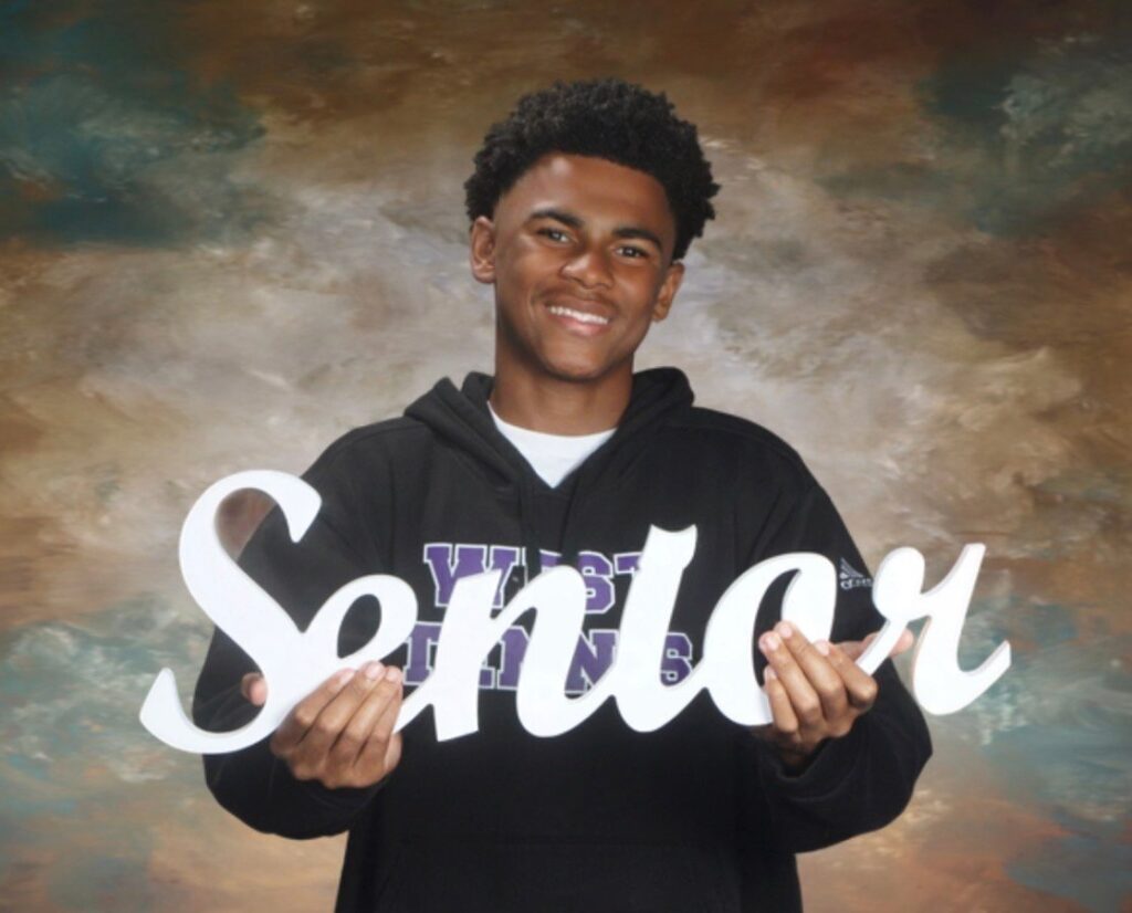 Noah Ezekiel holding a Senior sign for his graduation portrait