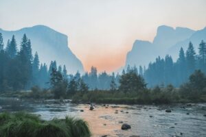 A river flowing through Yosemite Valley with granite cliffs and pine trees at low light. Non-identifying stock photograph.