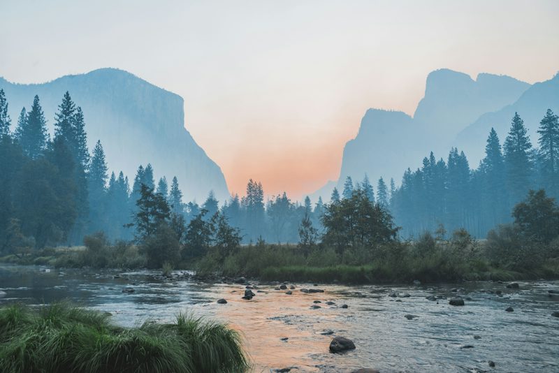 A river flowing through Yosemite Valley with granite cliffs and pine trees at low light. Non-identifying stock photograph.