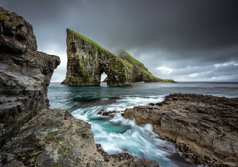 The Drangarnir sea stacks rising from the ocean under a dark, cloudy sky. Non-identifying stock photograph.