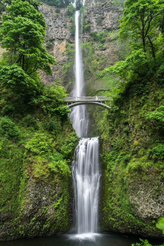 gray concrete bridge and waterfalls during daytime. Non-identifying stock photograph.